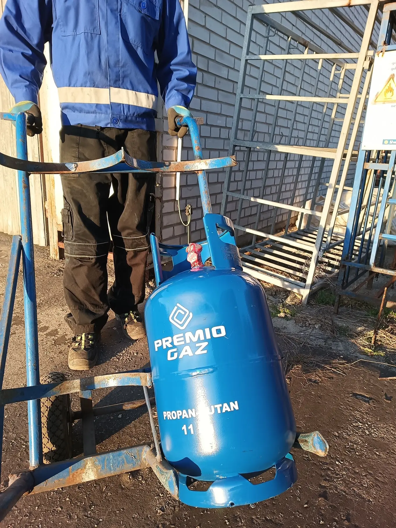 Pracownik firmy PremioGaz wiozący butlę wypełnioną gazem.