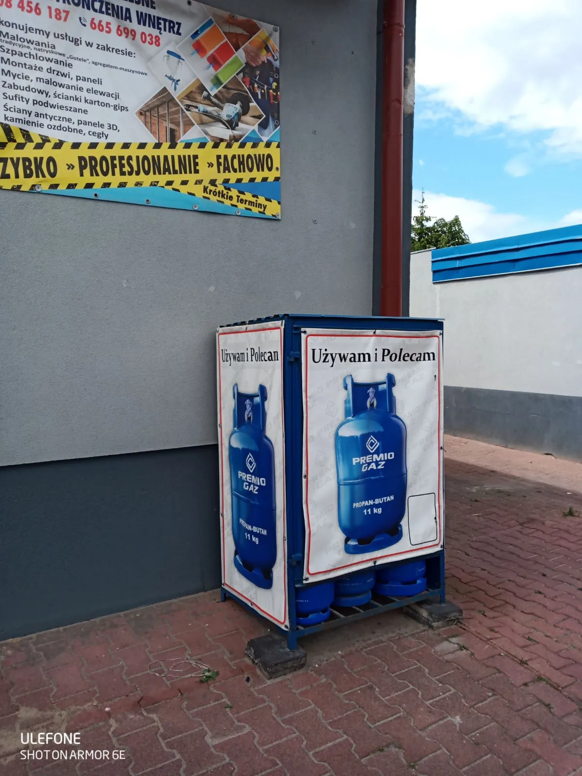 Skrzynka z butlami z gazem z naklejonym plakatem firmowym.